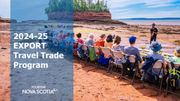 A group of 20 people eating a meal while sitting on one side of a banquet table on the beach at Burntcoat Head Park in the Bay of Fundy