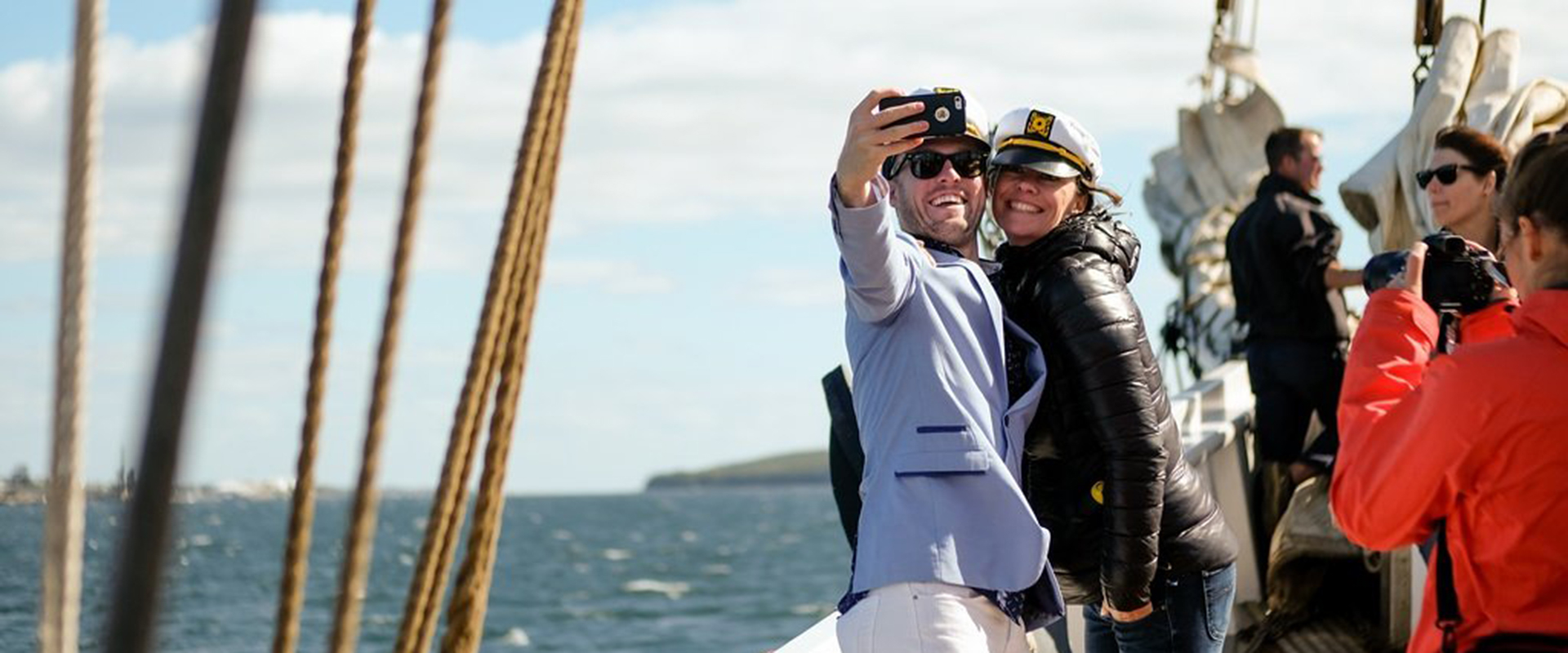 Couple taking a selfie on the Bluenose while media captures photos.