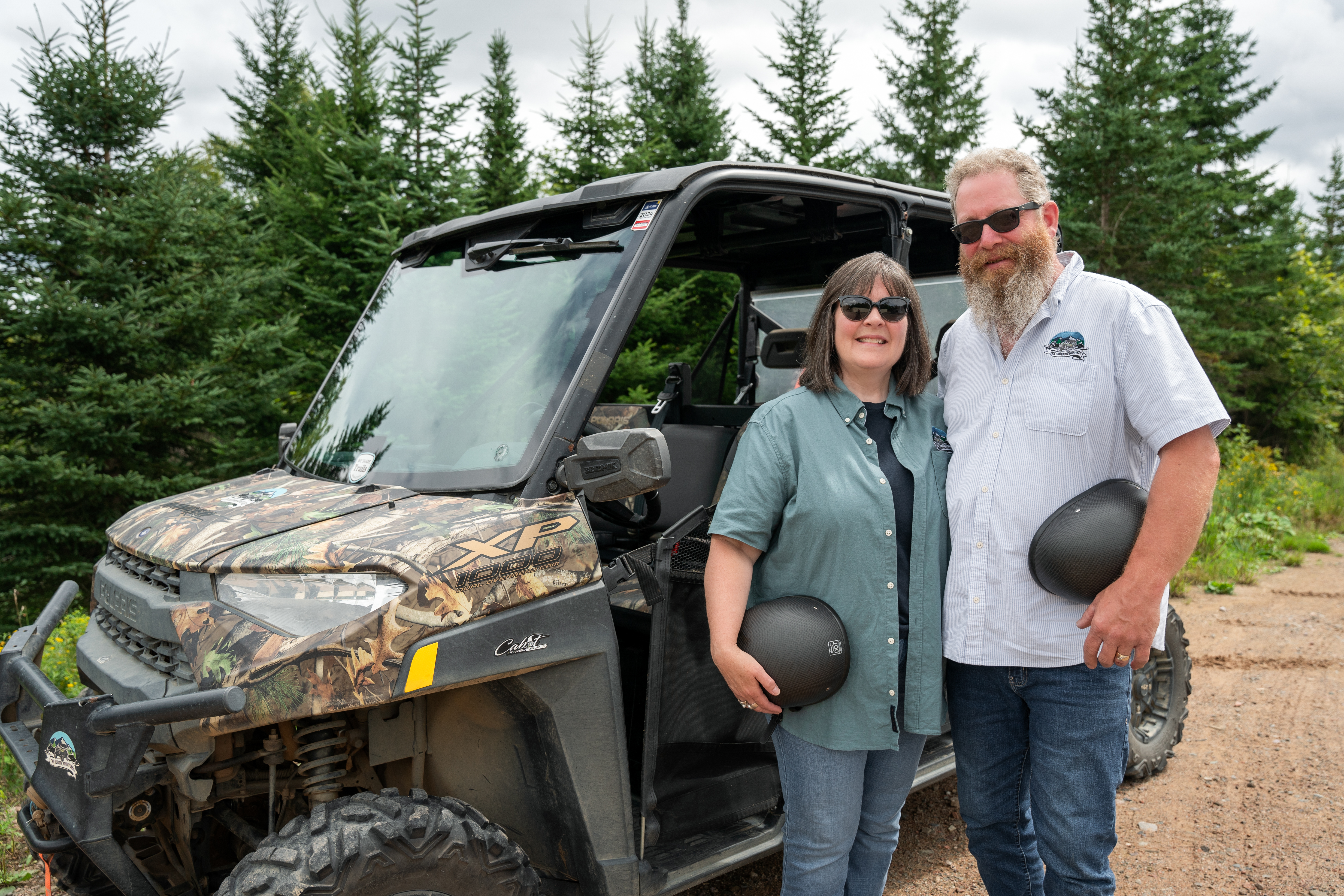 Two people standing in front of an four-wheeled off-road vehicle 