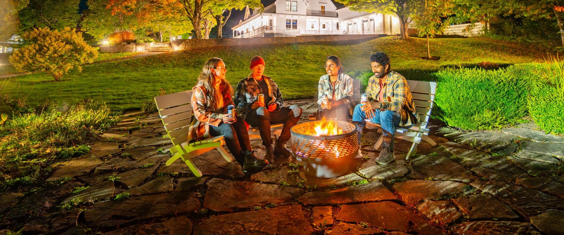 Four people sitting around a fire at a bed and breakfast.