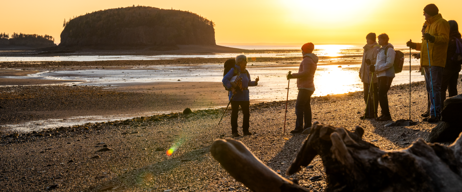 Mudlarkers Tours on the ocean floor. A tour group on the beach at sunset. 
