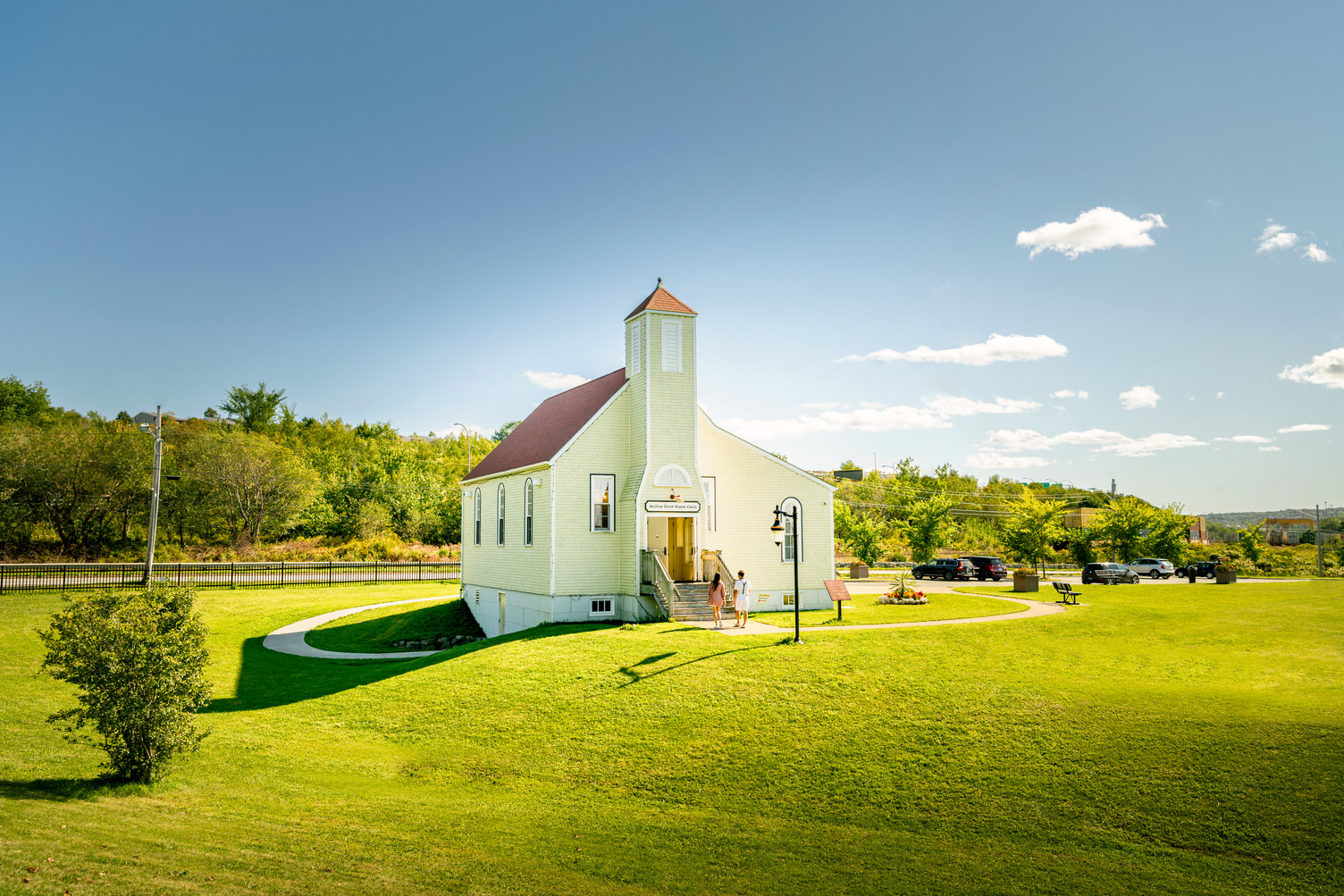 A small yellow church in the middle of a grass field