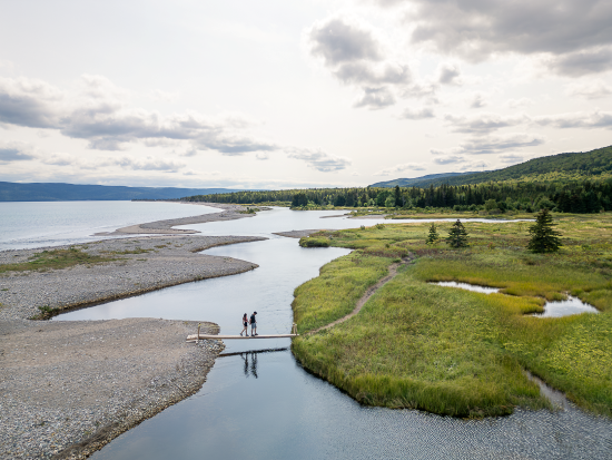 Two people walking across the wetlands at Cabot Shores Wilderness Resort. 