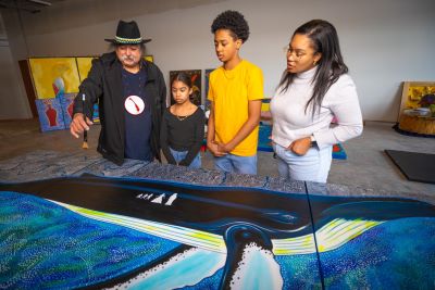 Mi'kmaw artist Alan Syliboy shows three children his artwork.