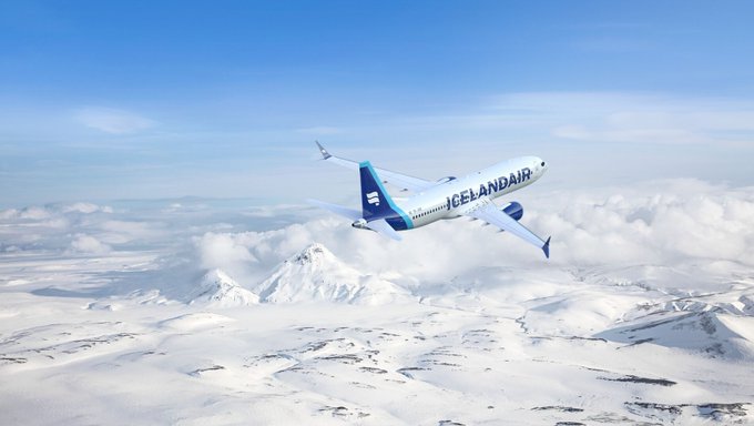 A white and blue plane flying over the snowy mountains