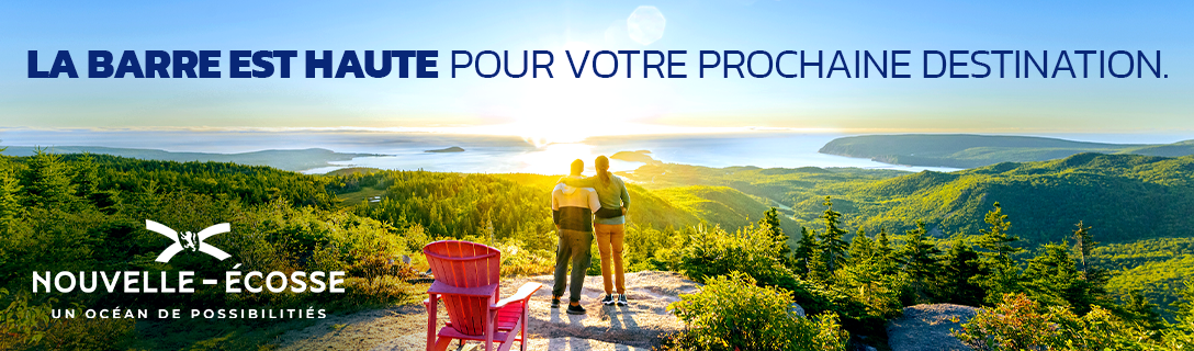French billboard showing two people standing at the top of Franey Trail in Cape Breton Highlands National Park. Text reads les barre est haute pour votre  prochane destination.