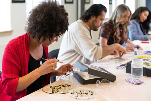 Guests align beads on a mosaic during an art experience. 