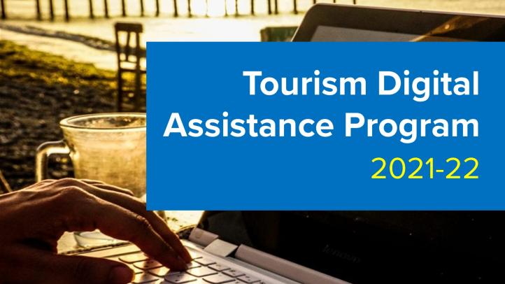 Hands typing on a laptop near the beach. Text reads: Tourism Digital Assistance Program 2021-22