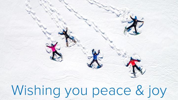 People making snow angels in an open field. Text reads: Wishing you peace & joy this holiday season