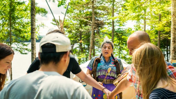 A group of people hold hands while participating in Eskasoni Cultural Journey experience on Goat Island.