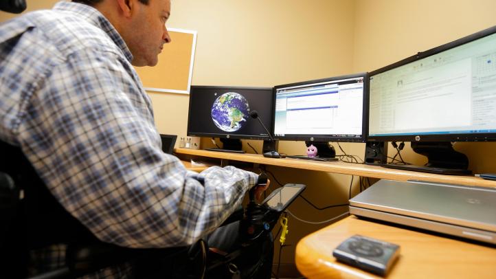 Man using communications assistive devices at a computer.