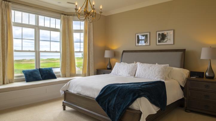 Light brown hotel room with white bed and French-style windows