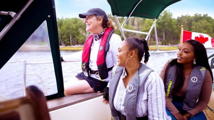 Three people in a boat looking out at Mahone Bay