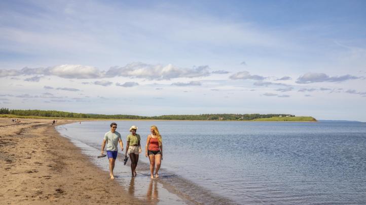 Three people walking along the beach enjoying a day at Pomquet Beach Provincial Park