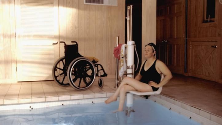 A person using an accessible ladder for the pool. 