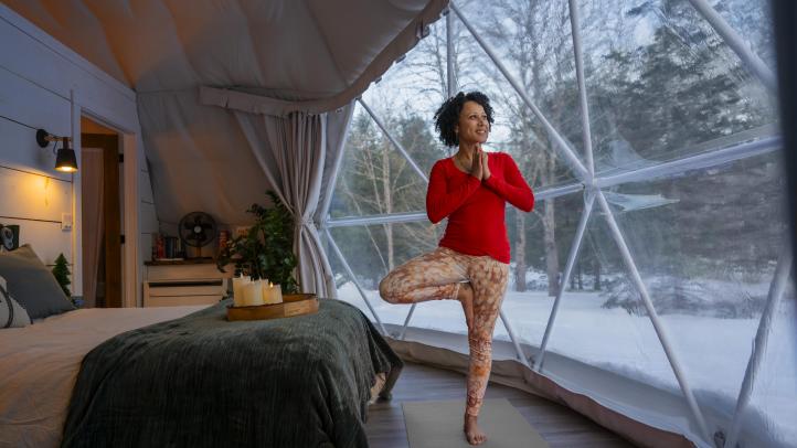 Women wearing read doing a yoga pose in a dome hotel in the winter