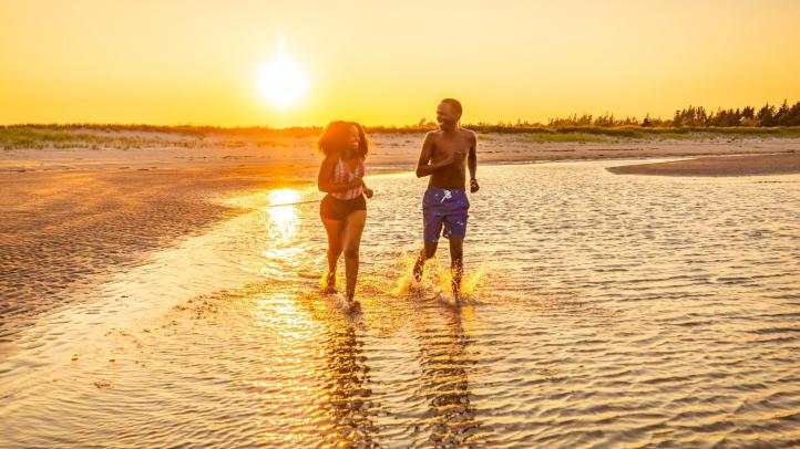 Two people running in the tide during sunset at Melmerby Beach Provincial Park.