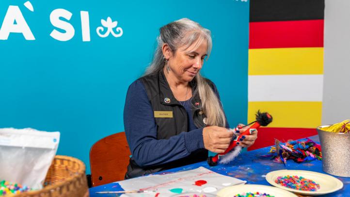 A Mi'kmaw artist is crafting at a table. 