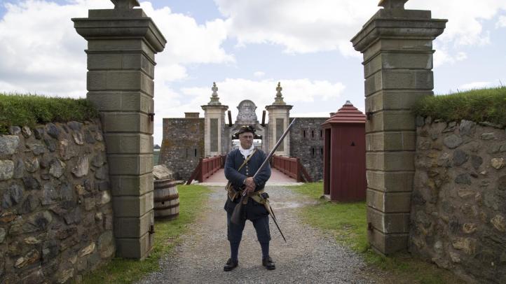 A costumed re-enactment employee stands at the gates of the Fortress of Louisbourg National Historic Site in Cape Breton. 