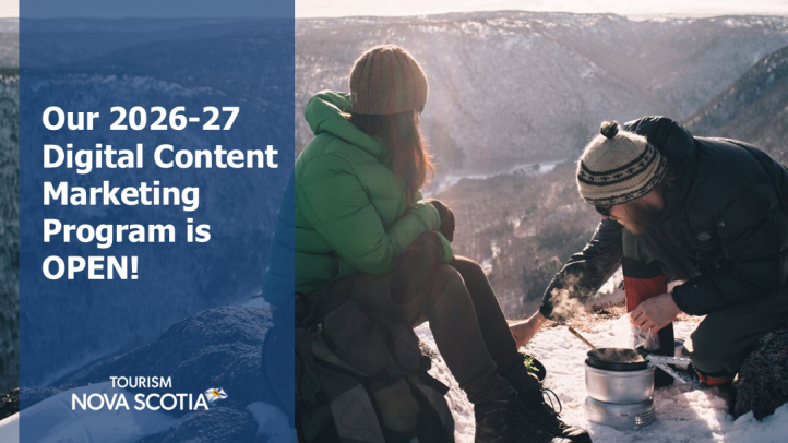 Two people on a snowy hilltop making a fire. 