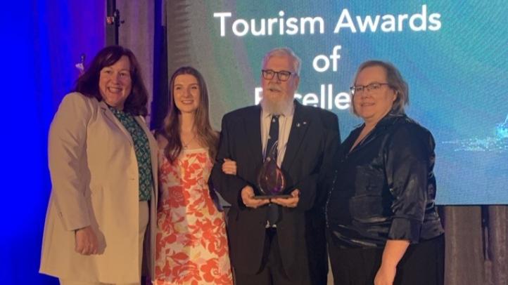 A group of four people standing with an award winner. 