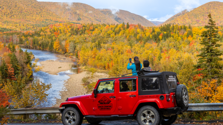 Two people enjoying a foliage tour in a Jeep. 