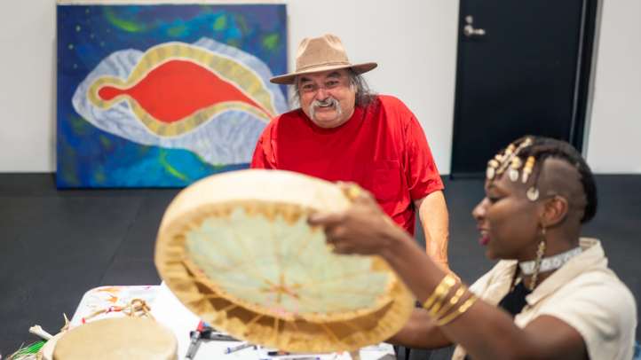 Alan Syliboy looks on as a student of his studio show him their drum. 