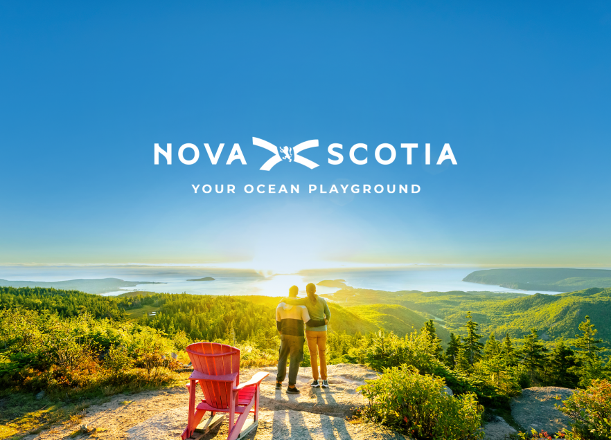 Two people at the top of Franey Trail in Cape Breton Highlands National Park. Text reads Nova Scotia Your Ocean Playground.