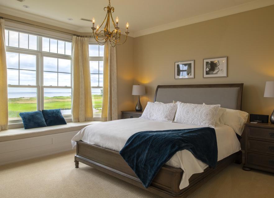 Light brown hotel room with white bed and French-style windows