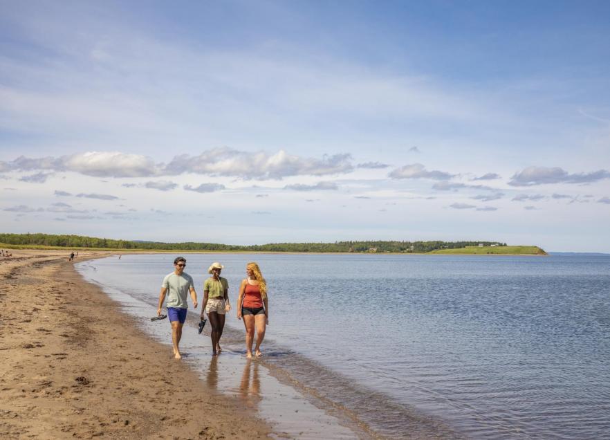 Three people walking along the beach enjoying a day at Pomquet Beach Provincial Park