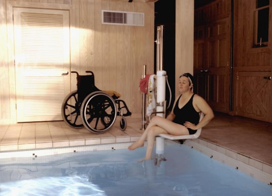 A person using an accessible ladder for the pool. 