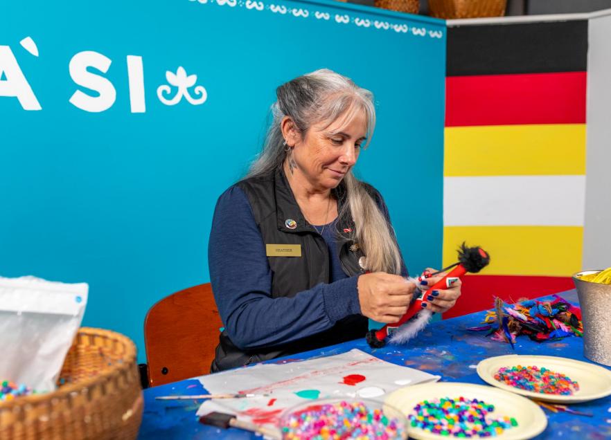 A Mi'kmaw artist is crafting at a table. 
