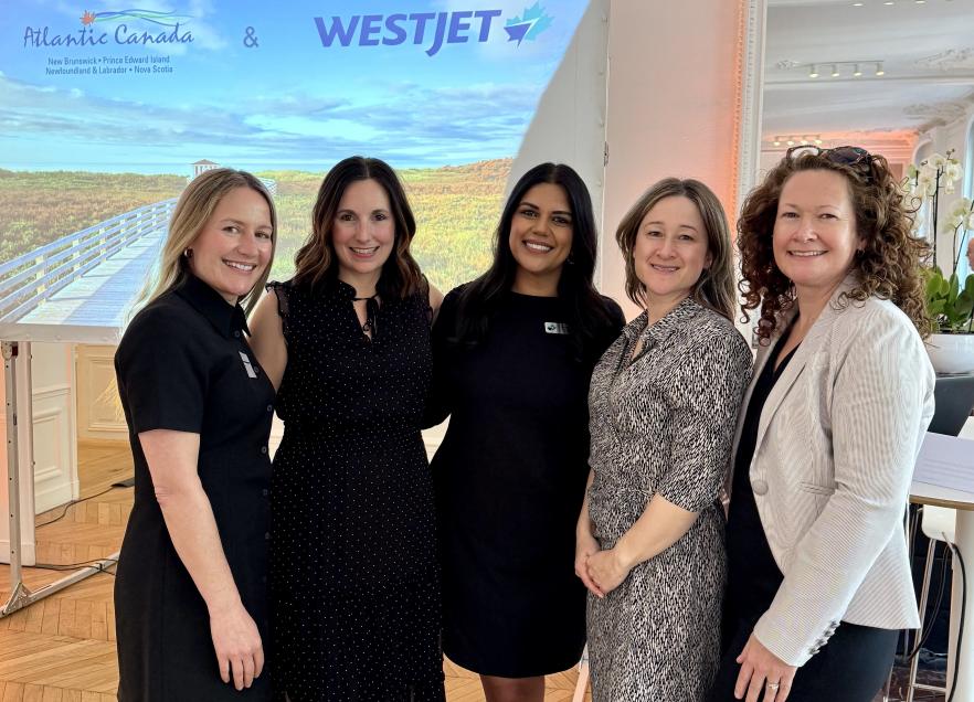 A group of five people stand together in front of a presentation about Atlantic Canada. 