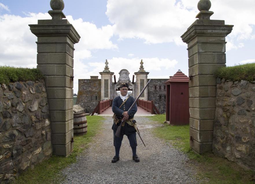 A costumed re-enactment employee stands at the gates of the Fortress of Louisbourg National Historic Site in Cape Breton. 