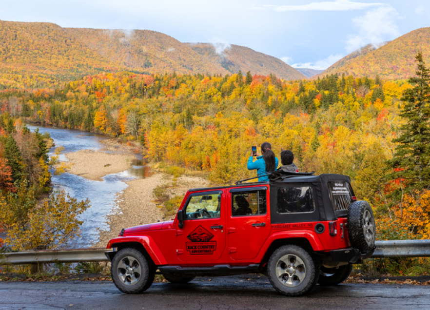 Two people enjoying a foliage tour in a Jeep. 