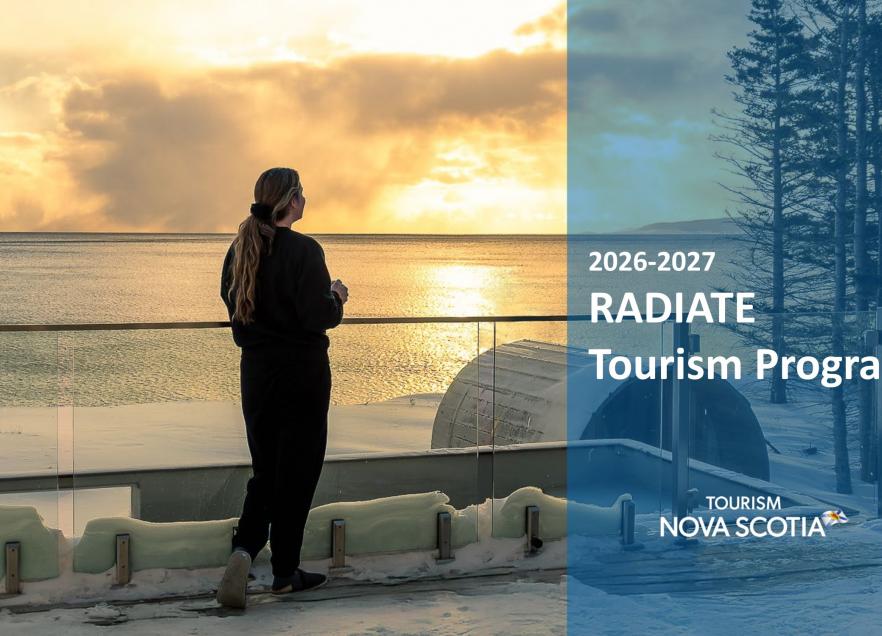 A person standing back to on a balcony holding a mug at sunset