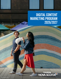 Two people walking together along the boardwalk in Halifax. One person has a cone of cotton candy. 