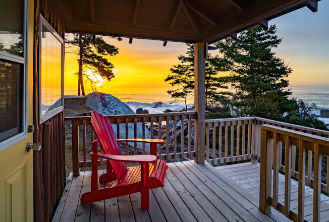 Red adriondack chair on a snowy cabin porch overlooking a winter vista